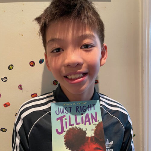 A young boy holds up a copy of his book “Just Right Jillian.”