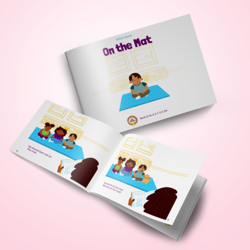 A book titled “On the Mat” is wide open. The book’s pages feature an illustration of children sitting on a mat.